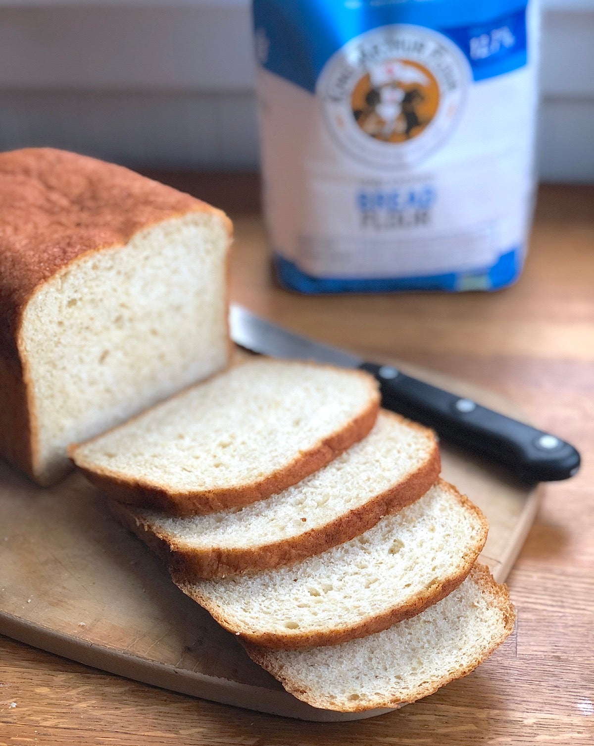 Oatmeal bread baked in a bread machine, sliced on a cutting board